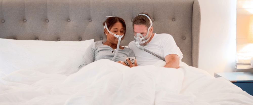 Two people wearing CPAP Masks researching sleep apnea treatment