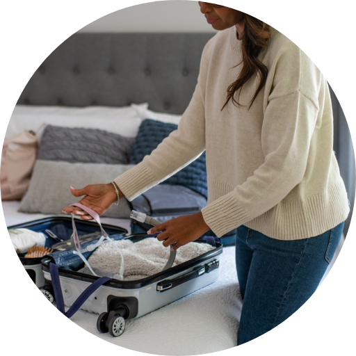 woman packing a nasal pillow cpap mask in her suitcase to treat her sleep apnea while traveling