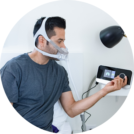 man adjusting the settings on a cpap machine while wearing a full face cpap mask
