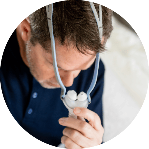 man putting on a nasal pillow cpap mask