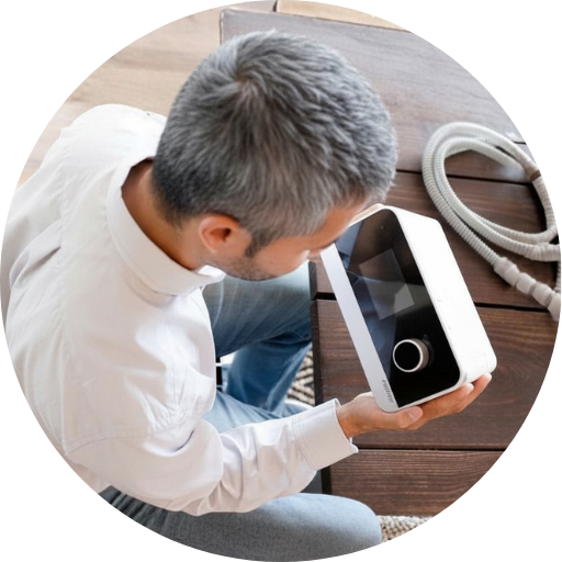 man looking down at a cpap machine he is holding for his sleep apnea treatment