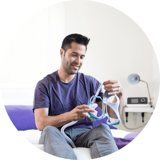 man looking at a full face cpap mask used for his obstructive sleep apnea treatment