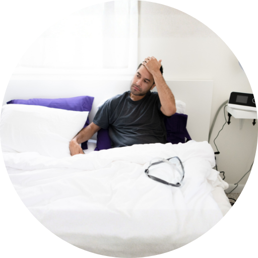 Man in bed with a CPAP mask waking up uncomfortable after CPAP therapy
