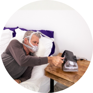 man wearing a CPAP mask adjusting a CPAP machine