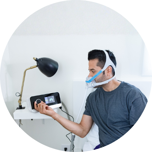 man adjusting the pressure settings on a cpap machine while wearing a full face cpap mask