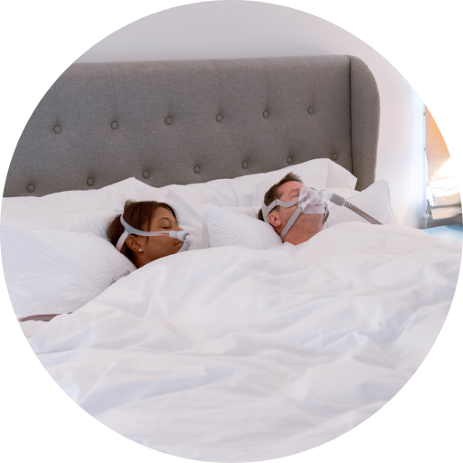 woman and man sleeping comfortably wearing CPAP masks and using CPAP Machines for their sleep apnea CPAP treatment