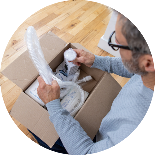 man opening a box containing replacement CPAP supplies and parts