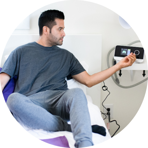 man sitting in bed adjusting the CPAP machine for sleep apnea