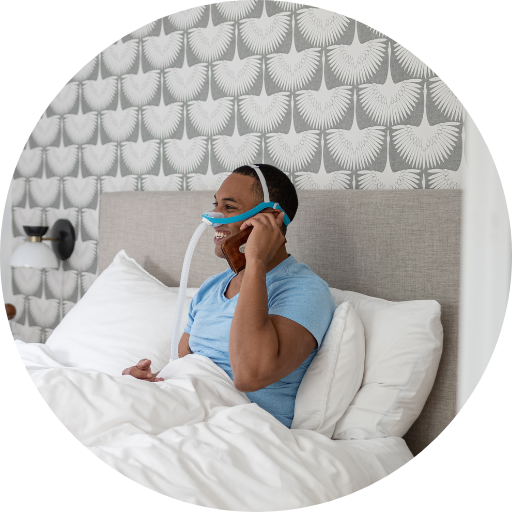 man wearing a nasal cpap mask while talking on the phone