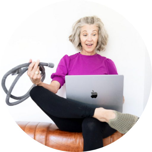 woman holding a CPAP machine hose while on the computer