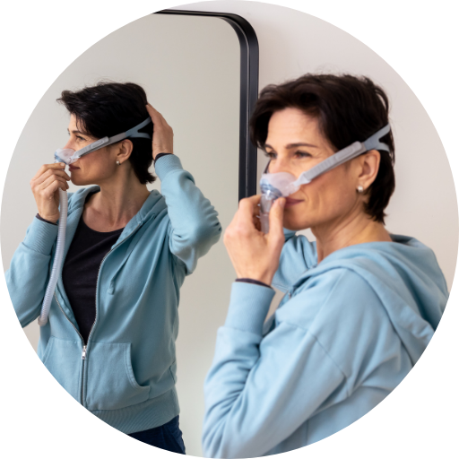 woman standing in the mirror trying on a nasal cpap mask
